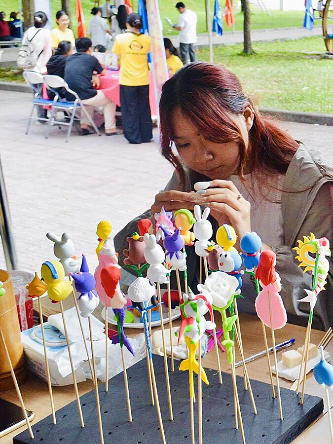 Một bạn trẻ chăm chú nặn tò he tại sự kiện ngoài trời